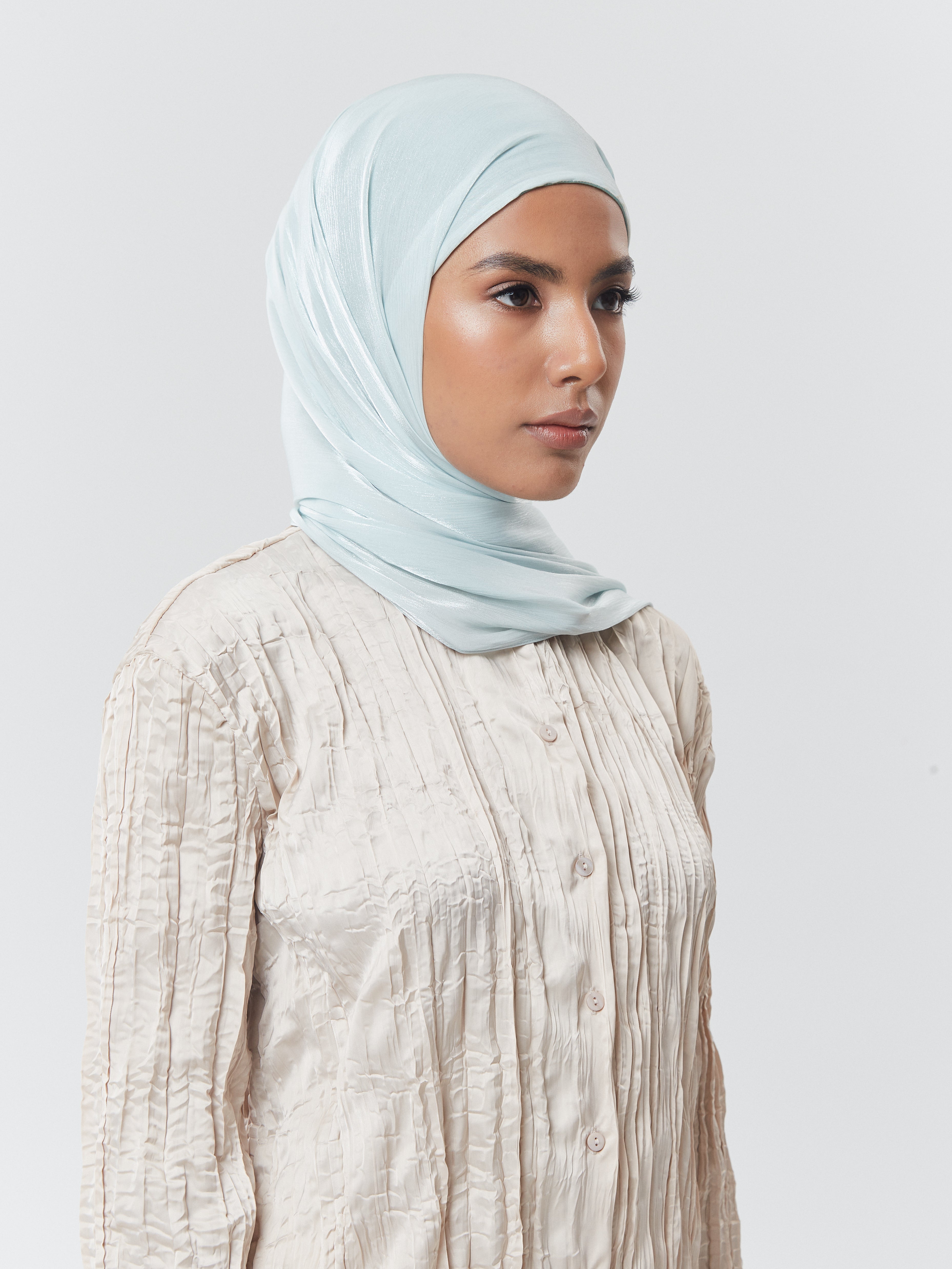 Side profile of woman wearing Yovlaq mint cream silk hijab styled with a cream textured blouse – elegant ready-to-wear modest fashion.
